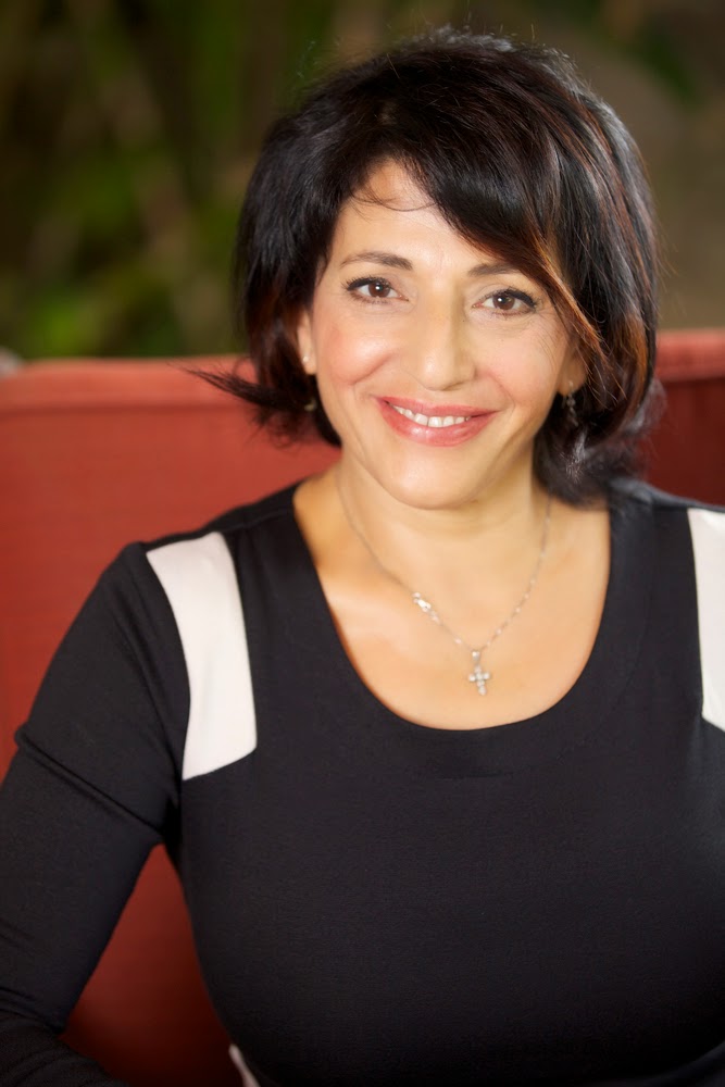 Sudabeh Jasmine-Zarififar, psychotherapist, smiling while seated in a red chair
